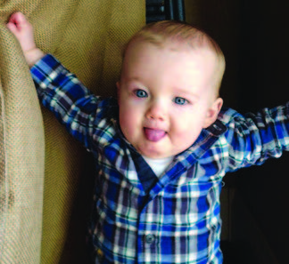 A small and clear image of a blonde toddler in plaid shirt sticking out their tongue.
